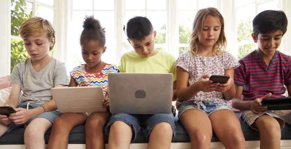 five children interacting with mobile devices and laptops