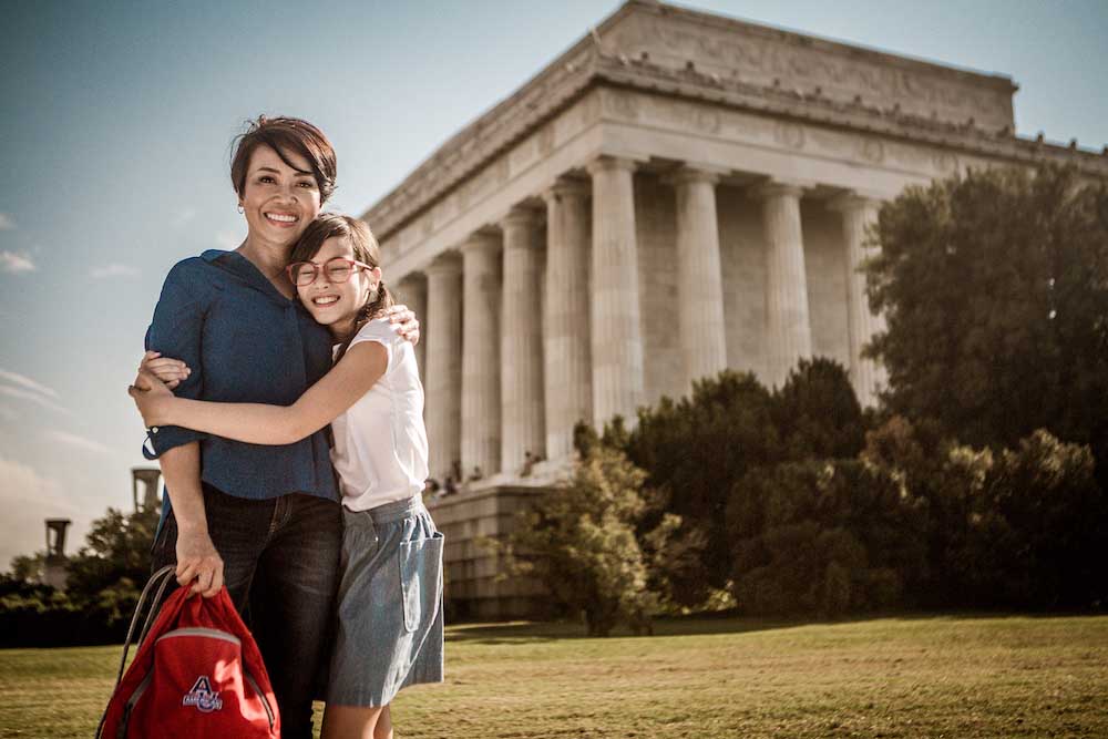 Two family members stand outside in front of a columned building.