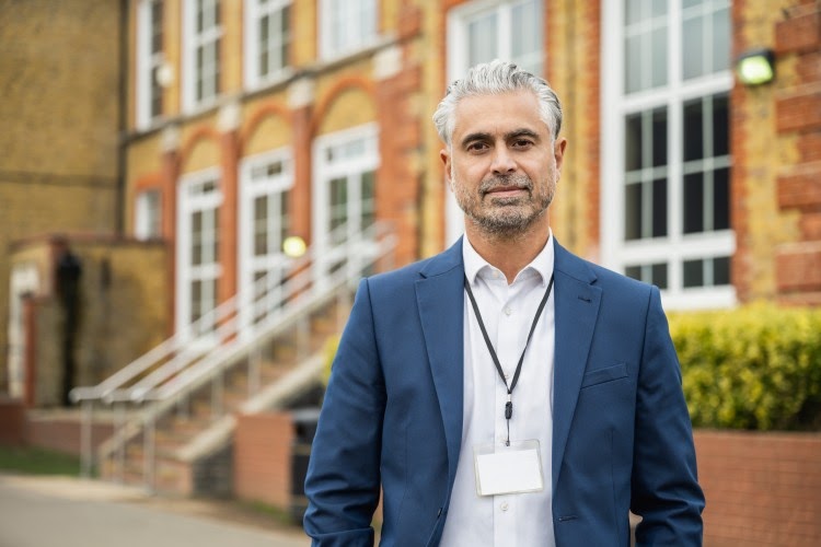 A principal standing outside of a school.