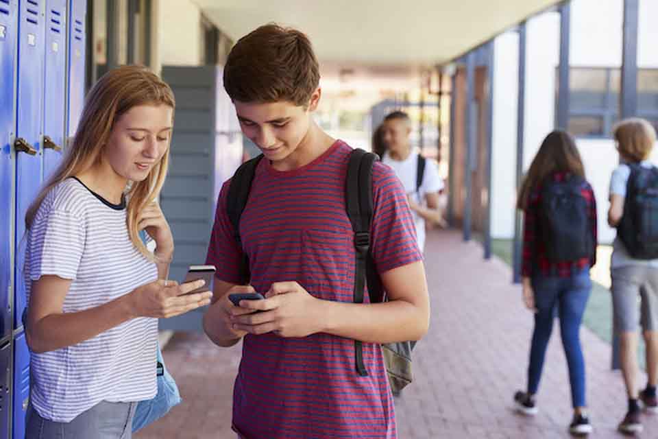 Two teenagers looking at their phones