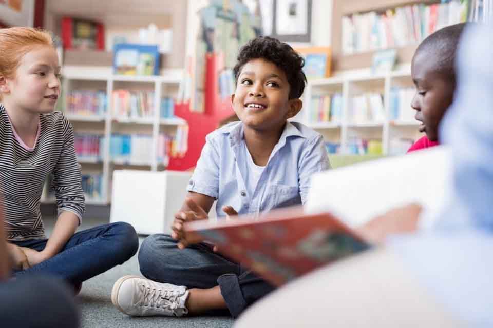 Teacher reads to elementary school children in library.