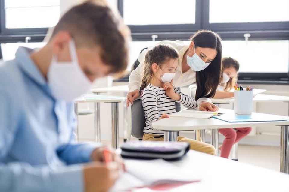 Teacher and students wearing face masks in a classroom.