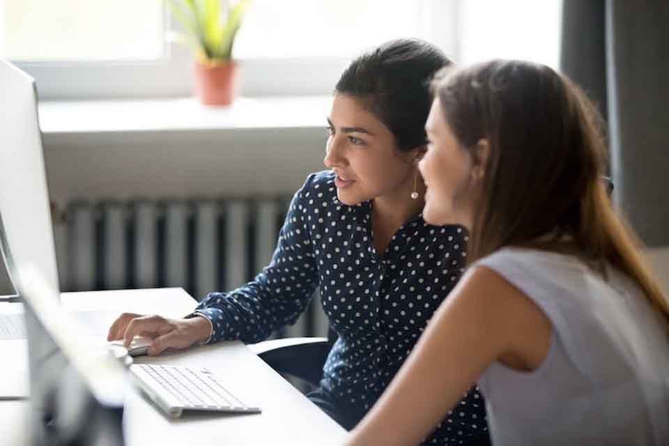 An educational consultant works with a student at a computer.