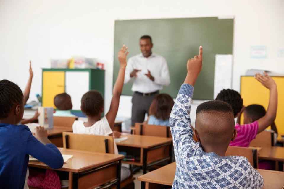 Schoolchildren raise their hands in class.