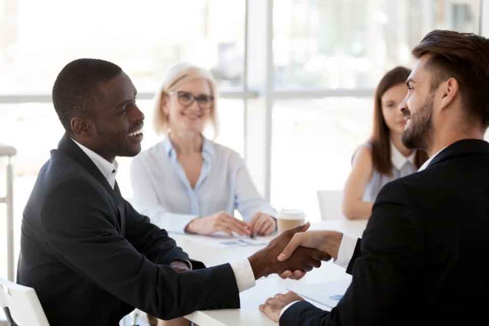 A candidate for a teaching job shakes hands with an interviewer during a group interview.