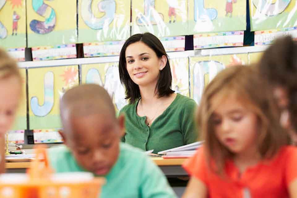 A teacher looking at her young class in satisfaction