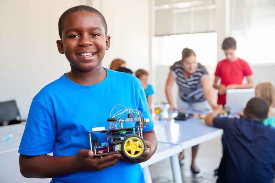 A young student holds a machine that he made.