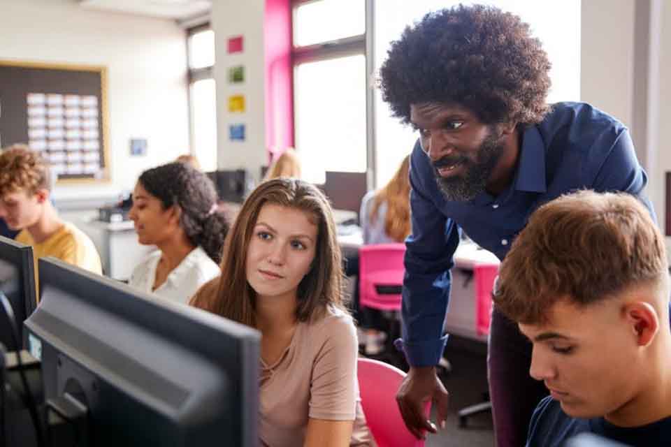 A teacher helps a student with a computer lesson.