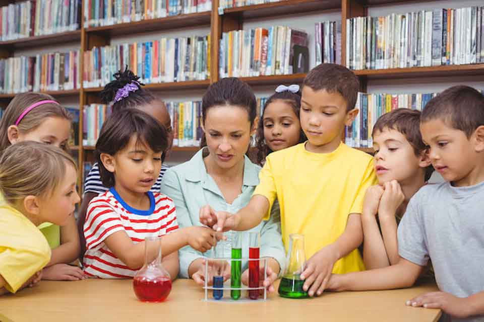 A woman and a group of children doing chemistry experiments