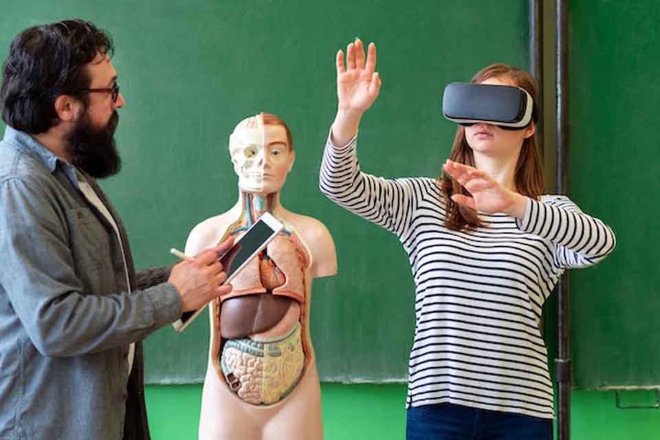 A male biology teacher instructs a female middle school student using virtual reality technology.