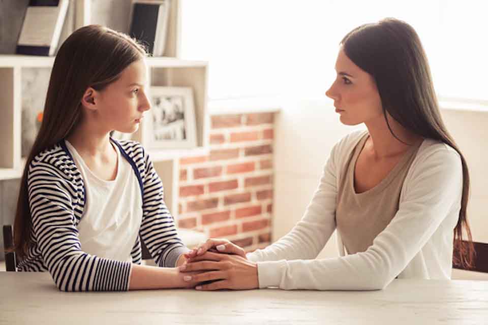 A woman and a girl looking at each other with serious facial expressions