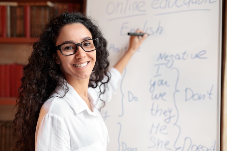 A smiling teacher or facilitator writes on a whiteboard.