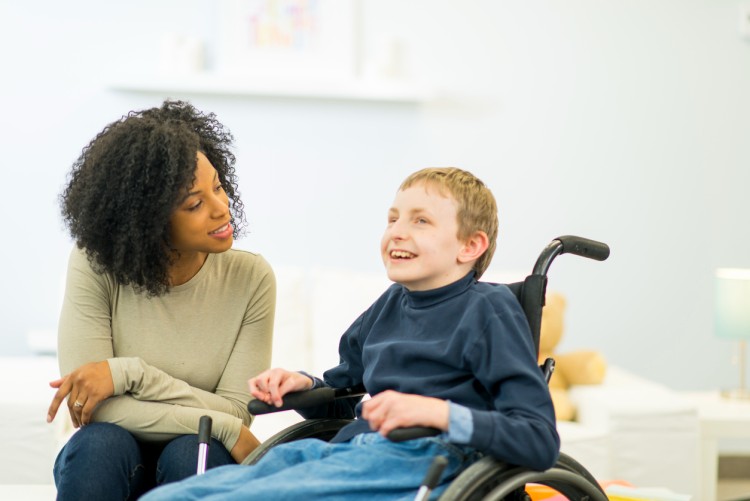 A special education teacher talks with a smiling student.