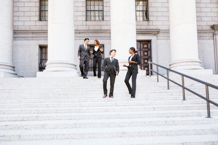 Professional colleagues walk down the steps of a government building.