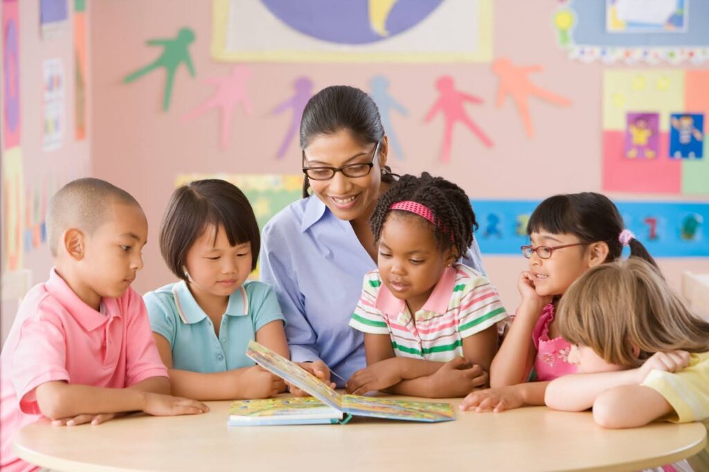 A teacher and a group of young students read a board book together.