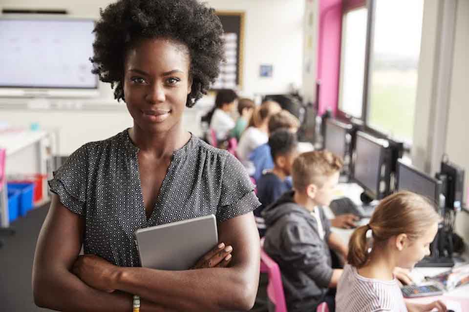 A teacher oversees a classroom of students working on computers.