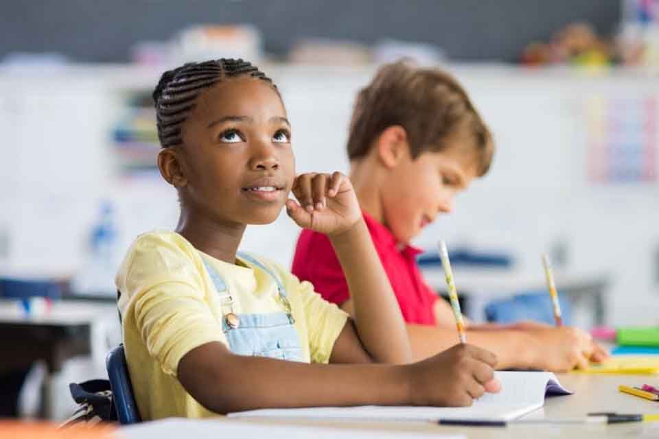 An elementary school student looks up from their notebook.