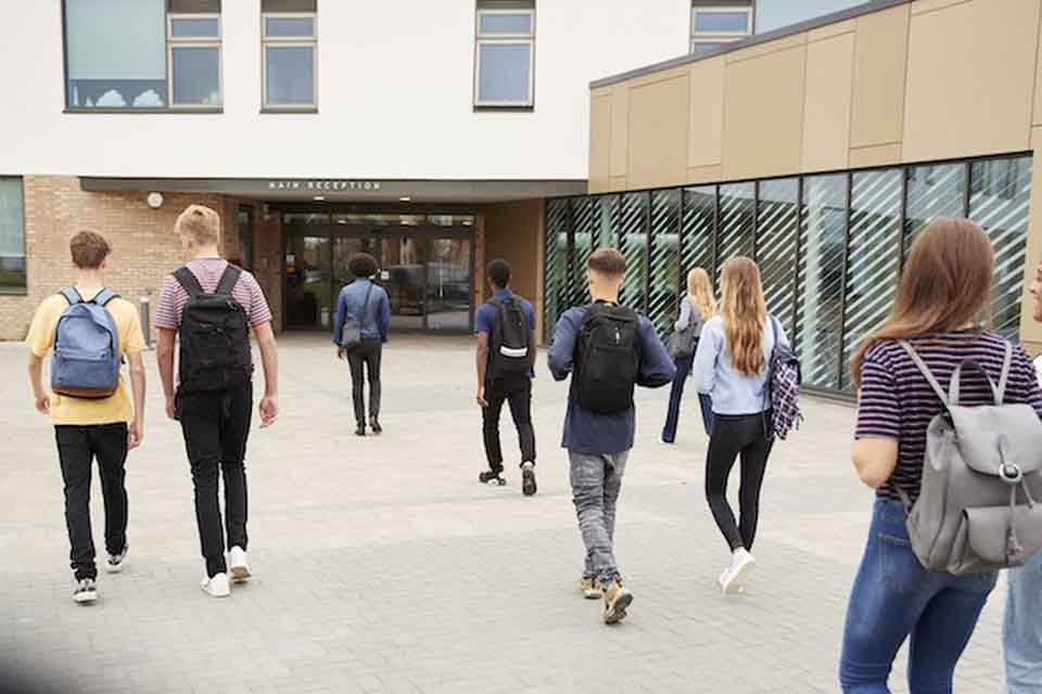 High school students walk into a school building.