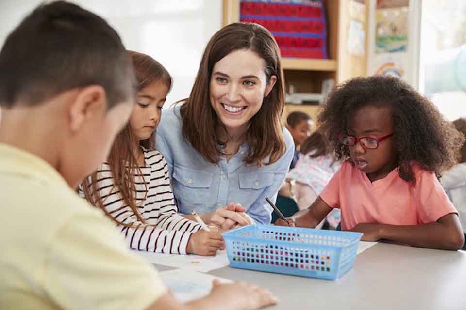 A teacher engages with a student group during a classroom activity.
