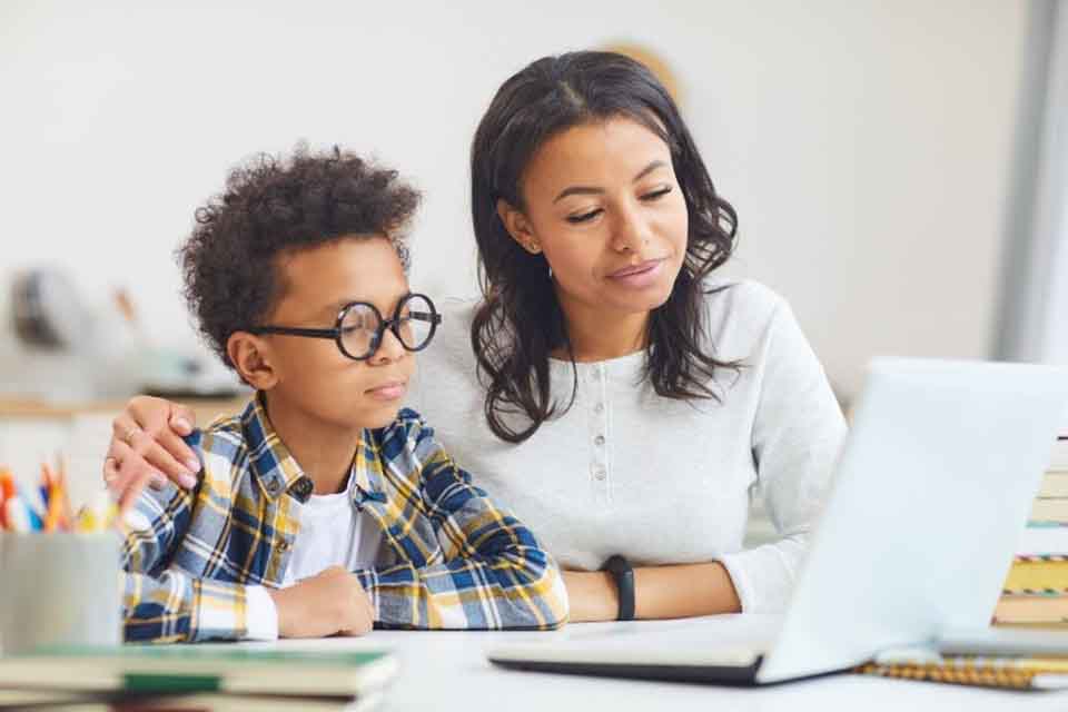 A mother and son work on a laptop as part of online learning.