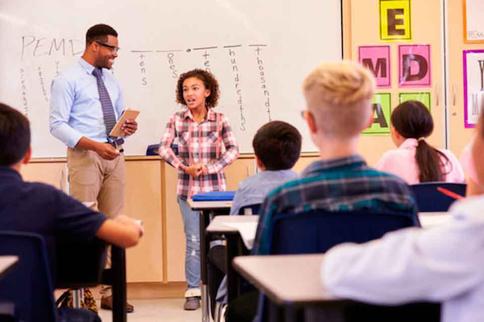 A teacher and a girl talking in front of a children's classroom