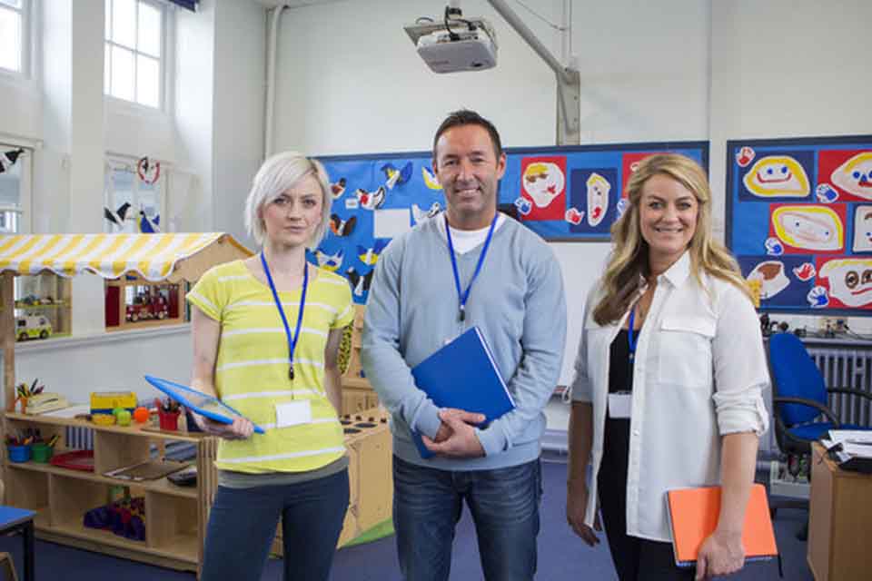 Three professors smiling standing in the middle of a classroom