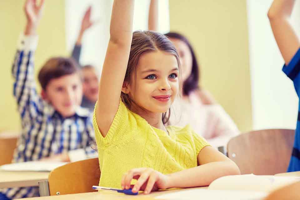 A girl in class with her hand raised