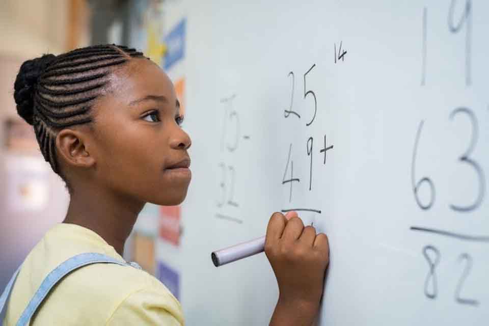 Student solves math problem on whiteboard.