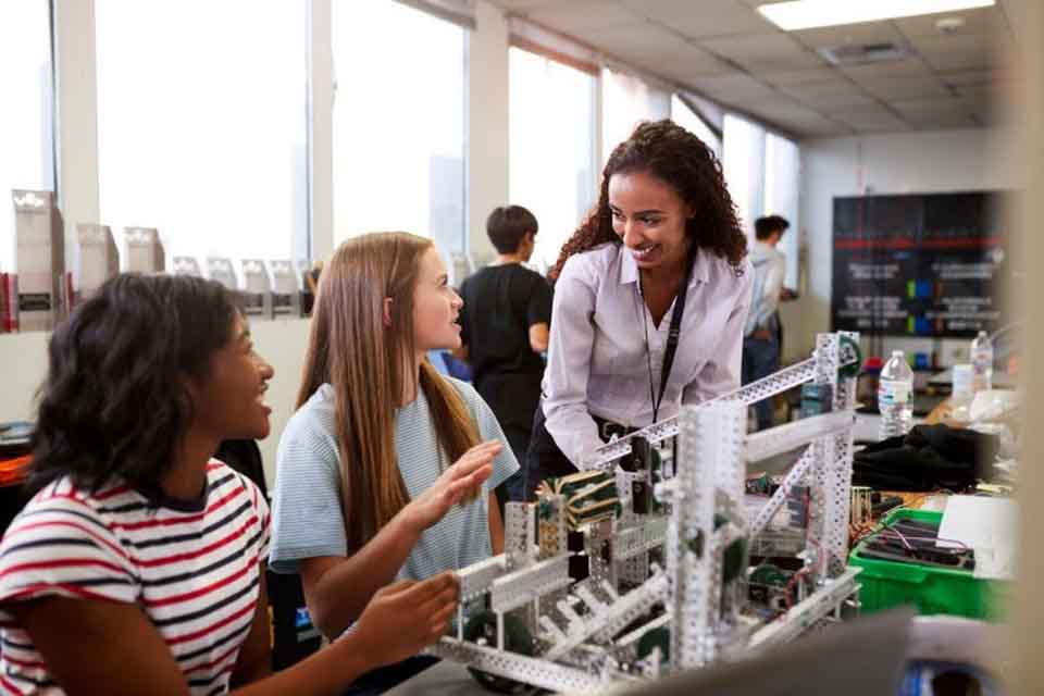 A teacher constructs a robot with her students.