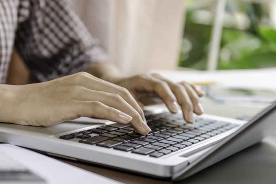 Hands working on the keyboard of a laptop.