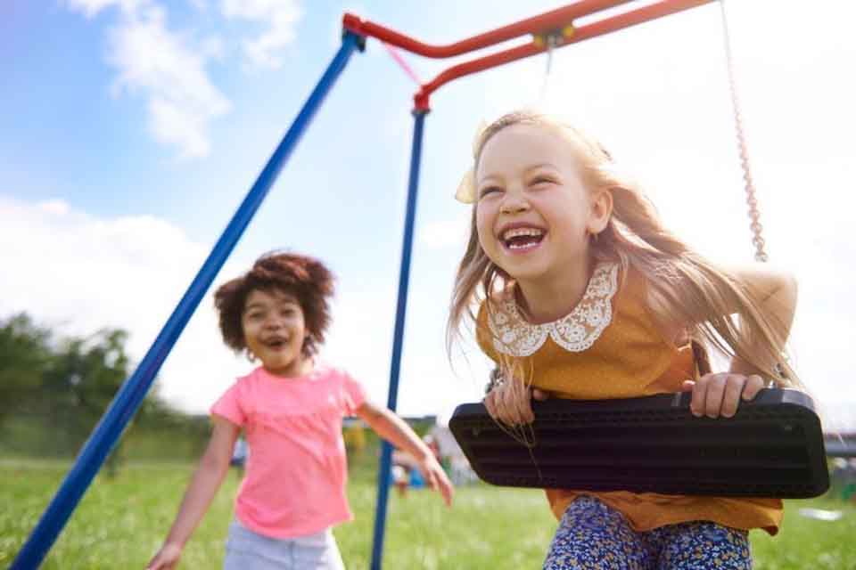 Two elementary school girls play on a swing set.