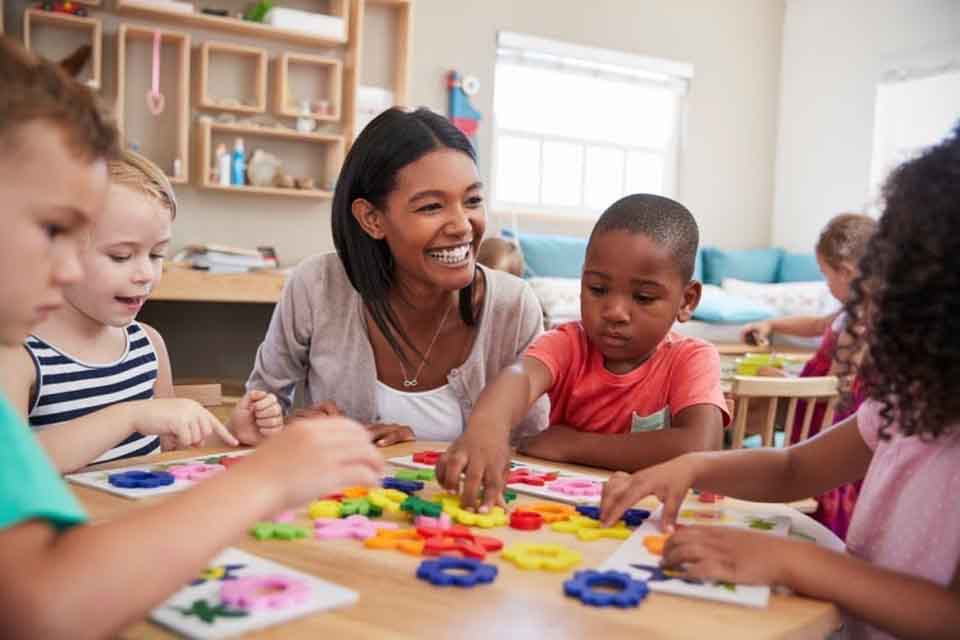 A smiling teacher works with her students.