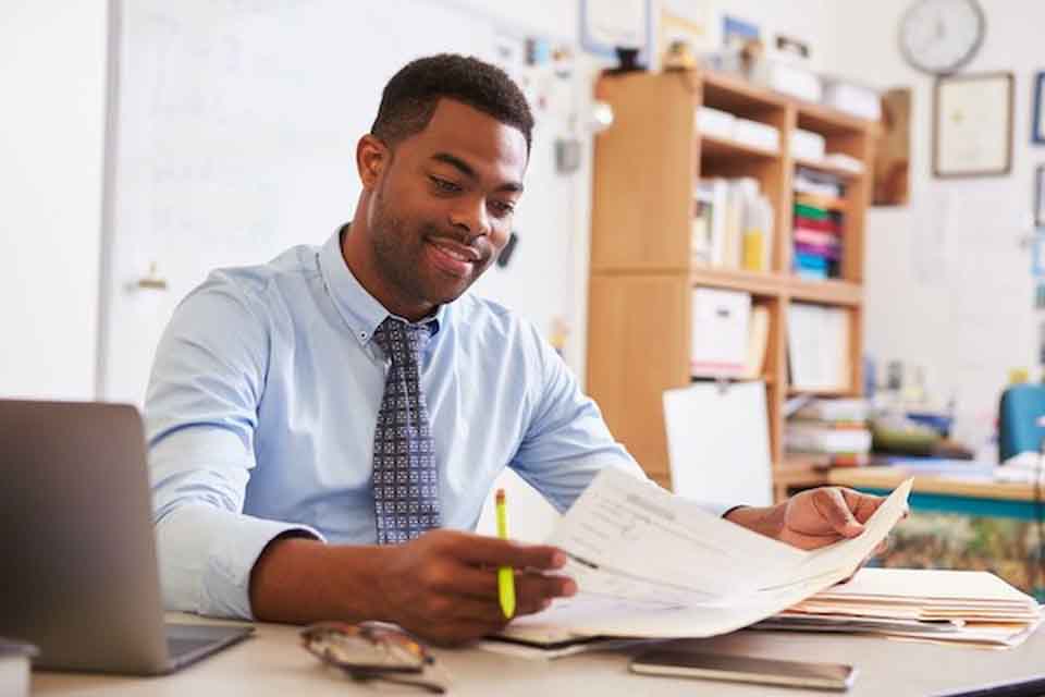 A man looking at a sheet of paper and smiling