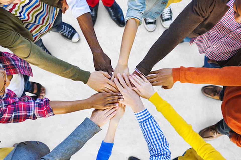 People putting their hands together in the middle of a circle