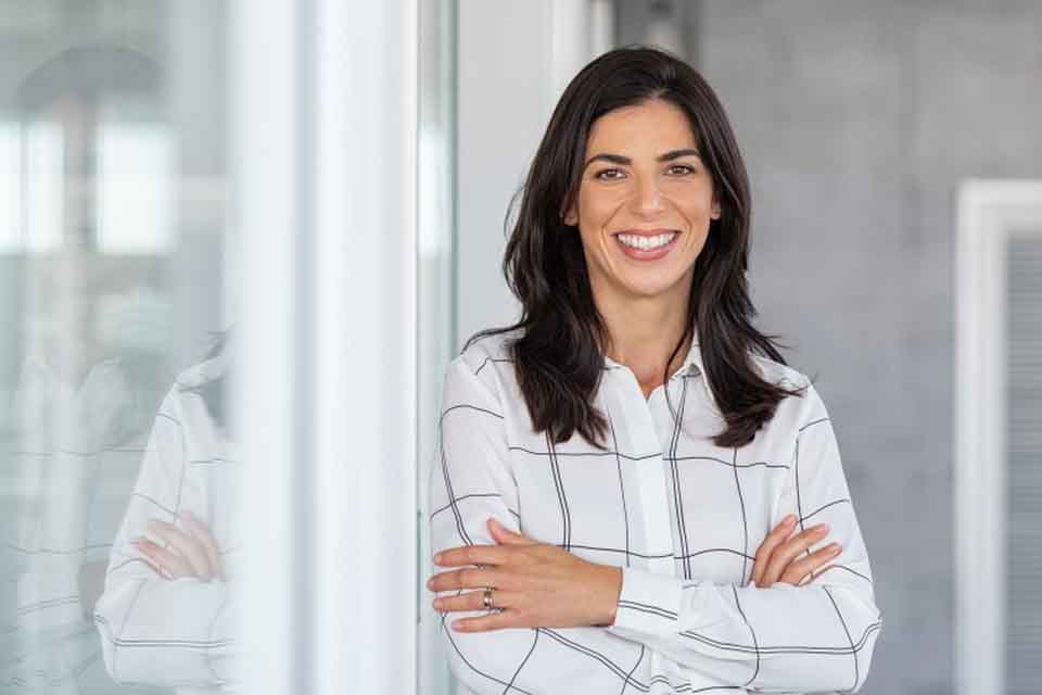 A smiling teacher stands by a whiteboard.