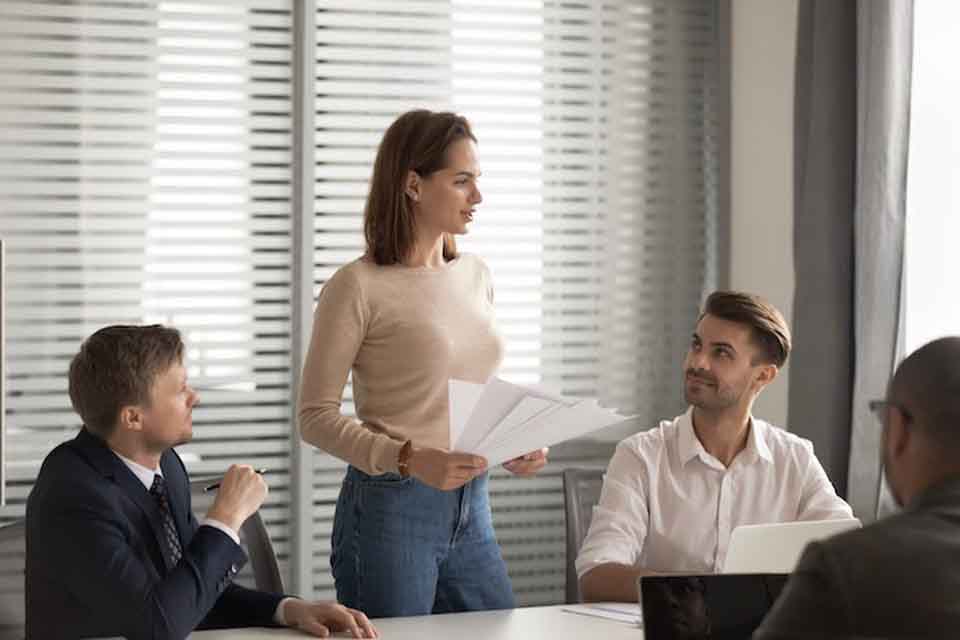 A female education leader mentors three male teachers in a conference room.