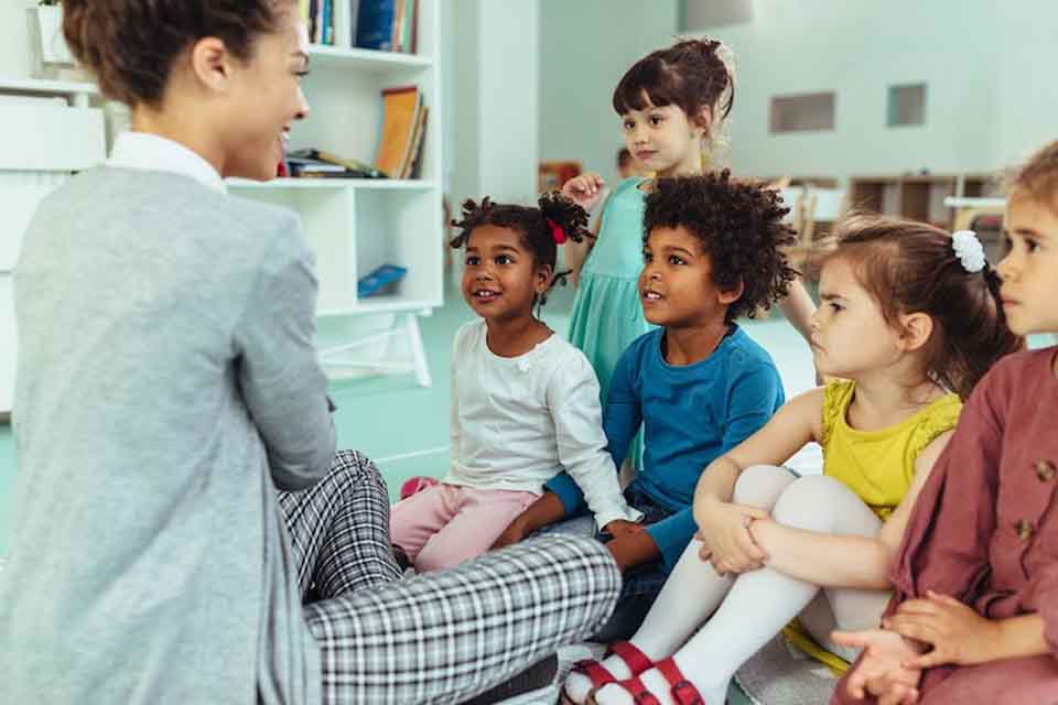 A kindergarten teacher engages students in discussion at circle time in a classroom.
