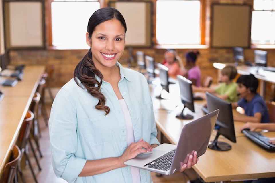 A teacher uses transformational leadership with her students in a classroom computer lab.