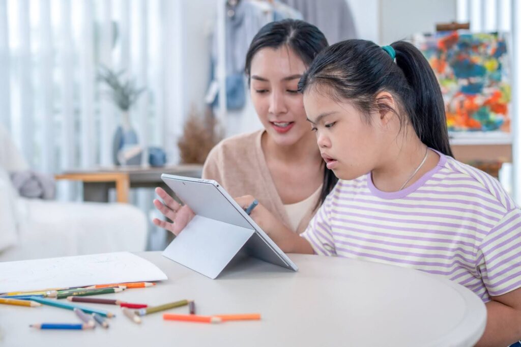 A teacher and an autistic student use an e-learning program on a tablet.